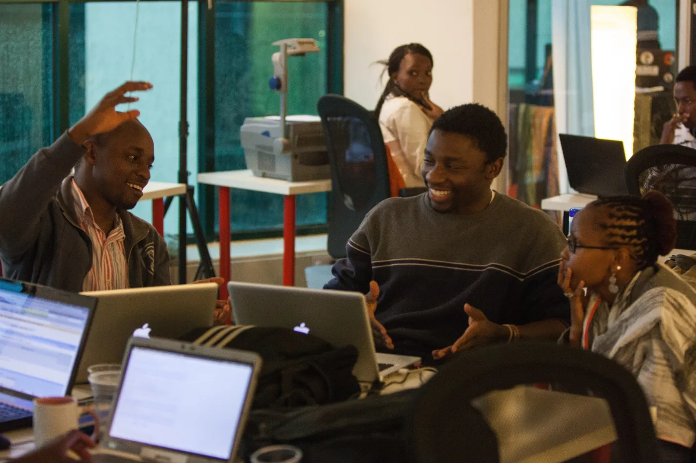 Developers laughing together over laptops at Science Hack Day Nairobi